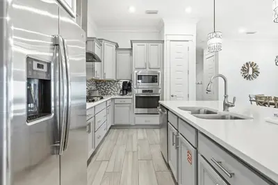 a kitchen with white cabinets and a stainless steel refrigerator at Prominence- 3 BR, steps to the resort style pool, Big Chill & Bikes in Santa Rosa Beach