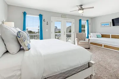 a bedroom with a white bed and a couch at New Kululu WEST- 3 BR, Sleeps 11, Heated Salt Water Pool, Bikes & moments from the beach in Santa Rosa Beach