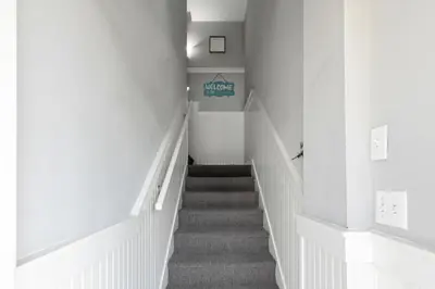 a hallway with a staircase with white walls and carpet at New Kululu WEST- 3 BR, Sleeps 11, Heated Salt Water Pool, Bikes & moments from the beach in Santa Rosa Beach