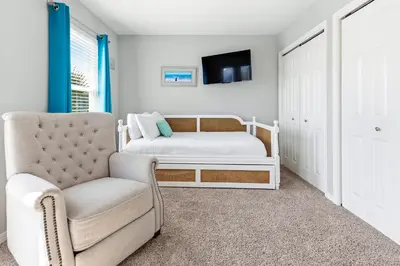 a bedroom with a bed and a chair and a tv at New Kululu WEST- 3 BR, Sleeps 11, Heated Salt Water Pool, Bikes & moments from the beach in Santa Rosa Beach