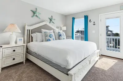a bedroom with a white bed and a window at New Kululu WEST- 3 BR, Sleeps 11, Heated Salt Water Pool, Bikes & moments from the beach in Santa Rosa Beach