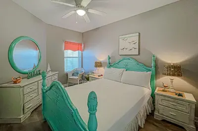 a bedroom with a green bed and a mirror at Beautifully decorated oceanfront condo with resort pool & huge walk-in showers in Santa Rosa Beach