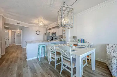 a kitchen and dining room with a table and chairs at Beautifully decorated oceanfront condo with resort pool & huge walk-in showers in Santa Rosa Beach