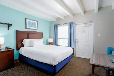 a bedroom with a large bed and a wooden table at Bikini Beach Resort in Panama City Beach