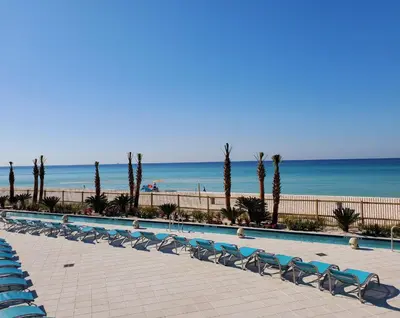 a row of chairs next to a swimming pool next to the beach at Holiday Inn Resort Panama City Beach by IHG in Panama City Beach