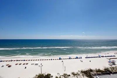 a beach with chairs and umbrellas and the ocean at Regency Towers by Panhandle Getaways in Panama City Beach