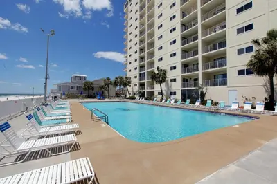 a swimming pool with lounge chairs and a building at Regency Towers by Panhandle Getaways in Panama City Beach