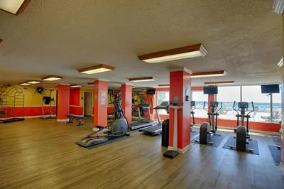 a gym with several treadmills and elliptical machines at Regency Towers by Panhandle Getaways in Panama City Beach