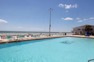 a large swimming pool with chairs and the beach at Regency Towers by Panhandle Getaways in Panama City Beach