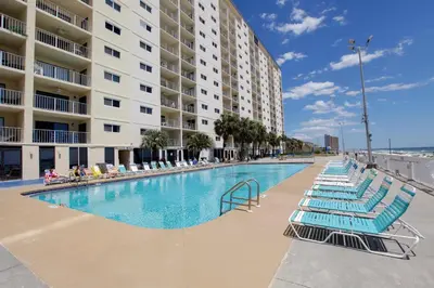 a swimming pool with blue lounge chairs and a building at Regency Towers by Panhandle Getaways in Panama City Beach