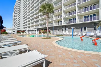 a resort pool with chairs and a palm tree at Laketown Wharf Resort by Panhandle Getaways in Panama City Beach