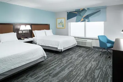 a hotel room with two beds and a chair at Hampton Inn & Suites Panama City Beach-Pier Park Area in Panama City Beach