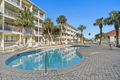 a swimming pool in front of a building with palm trees at Horizon South by Panhandle Getaways in Panama City Beach