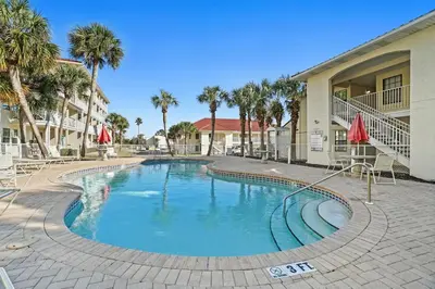 a swimming pool in front of a building with palm trees at Horizon South by Panhandle Getaways in Panama City Beach