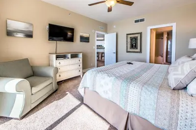a bedroom with a bed and a couch and a flat screen tv at Calypso 1-609 East in Panama City Beach