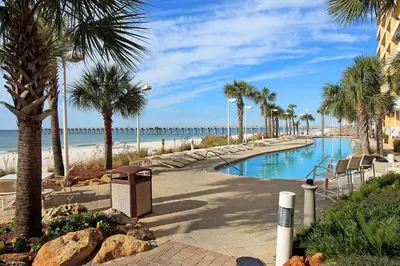 a swimming pool with palm trees and a beach at Calypso 1-609 East in Panama City Beach