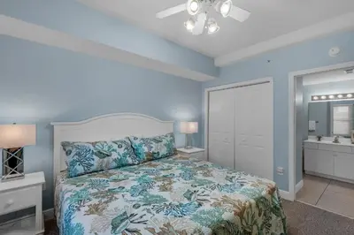 a bedroom with a bed with blue walls at Celadon 309 in Panama City Beach