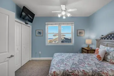 a bedroom with a bed with a ceiling fan and a window at Celadon 309 in Panama City Beach