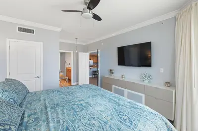 a bedroom with a bed and a flat screen tv at Grandview East 1203 in Panama City Beach