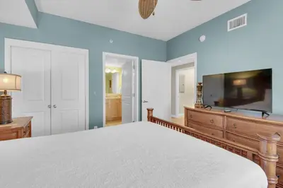 a bedroom with a large bed and a flat screen tv at Grandview East 1204 in Panama City Beach