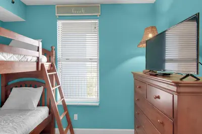 a bedroom with a bunk bed and a dresser with a television at Grandview East 1204 in Panama City Beach