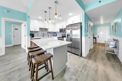 a kitchen with white and blue walls and wooden floors at Laketown Wharf 1326 in Panama City Beach