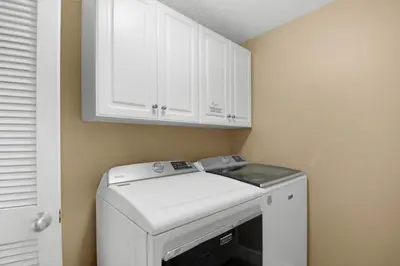 a washer and dryer in a laundry room with white cabinets at Majestic Beach Towers 2-1905 in Panama City Beach