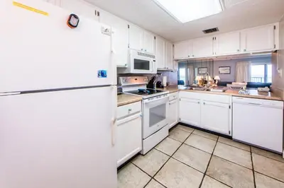 a kitchen with white cabinets and a white refrigerator at Moonspinner 211B - PCB East in Panama City Beach
