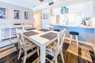 a kitchen with a white table and chairs in a room at Moonspinner 211B - PCB East in Panama City Beach