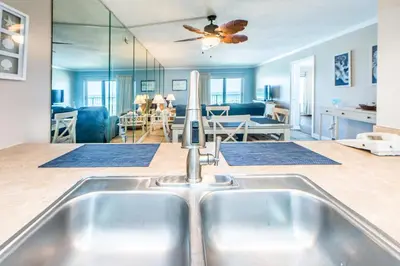 a kitchen with a sink and a living room at Moonspinner 211B - PCB East in Panama City Beach