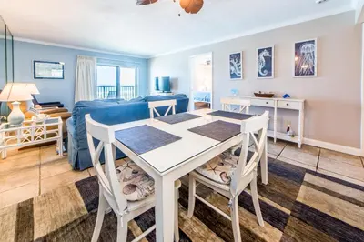 a dining room and living room with a table and chairs at Moonspinner 211B - PCB East in Panama City Beach