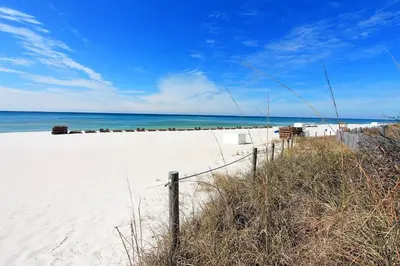 a fence on a beach with the ocean in the background at Moonspinner 211B - PCB East in Panama City Beach