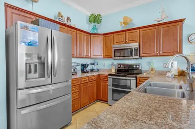 a kitchen with wooden cabinets and stainless steel appliances at Ocean Villa Penthouse #2302 in Panama City Beach