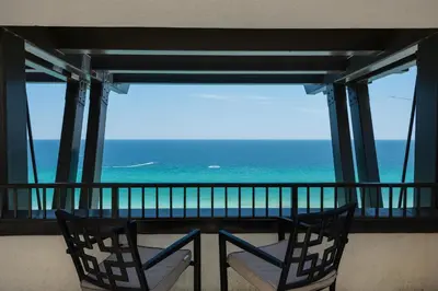 a balcony with two chairs and a view of the ocean at Origin at Seahaven 825 in Panama City Beach