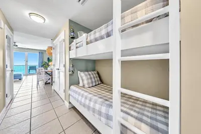 a bedroom with bunk beds and a hallway with a desk at Seychelles 1504 in Panama City Beach