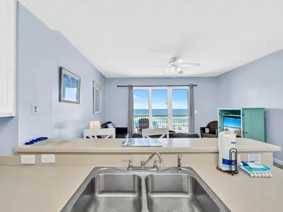a kitchen with a sink and a living room at Seychelles 207 in Panama City Beach