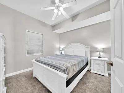 a white bedroom with a bed and a ceiling fan at Seychelles 207 in Panama City Beach