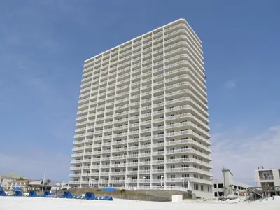 a tall white building on the beach with the sand at Seychelles 207 in Panama City Beach