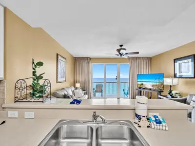a kitchen with a sink and a living room at Seychelles 907 in Panama City Beach