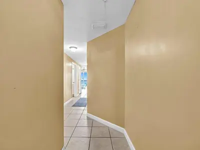 a hallway with yellow walls and a tile floor at Seychelles 907 in Panama City Beach