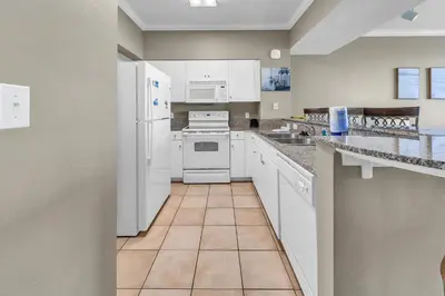 a kitchen with white appliances and a tile floor at Shores of Panama 2112 in Panama City Beach
