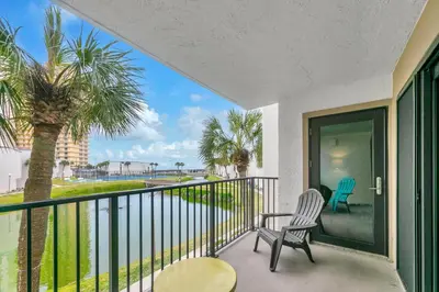 a balcony with two chairs and a palm tree at Sugar Beach C-2 in Panama City Beach