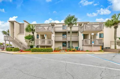 a large apartment building with palm trees in a parking lot at Sugar Beach C-2 in Panama City Beach