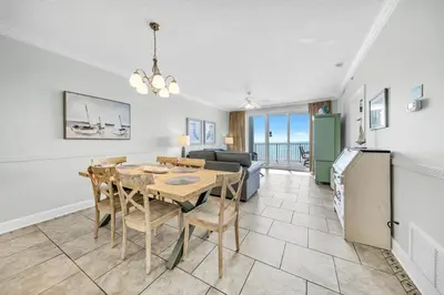 a dining room and living room with a table and chairs at Twin Palms 804 in Panama City Beach