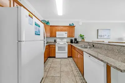 a kitchen with white appliances and wooden cabinets at Twin Palms 804 in Panama City Beach