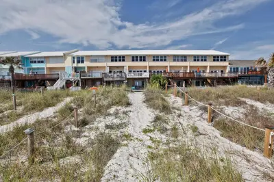 a building on the beach with a sandy path in front at Beachside West Townhome in Panama City Beach