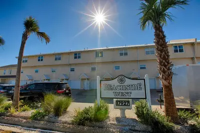 a sign in front of a building with palm trees at Beachside West Townhome in Panama City Beach