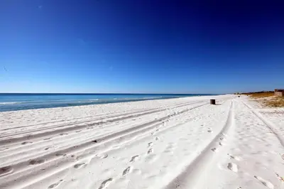 a beach with footprints in the sand and the ocean at Beachside West Townhome in Panama City Beach