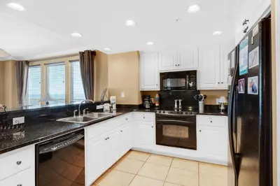 a kitchen with white cabinets and a black refrigerator at Treasure Island 2212 in Panama City Beach