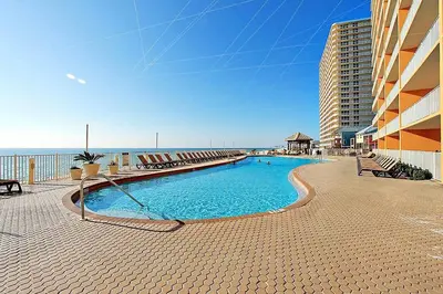 a swimming pool in front of a building next to the ocean at Treasure Island 2212 in Panama City Beach